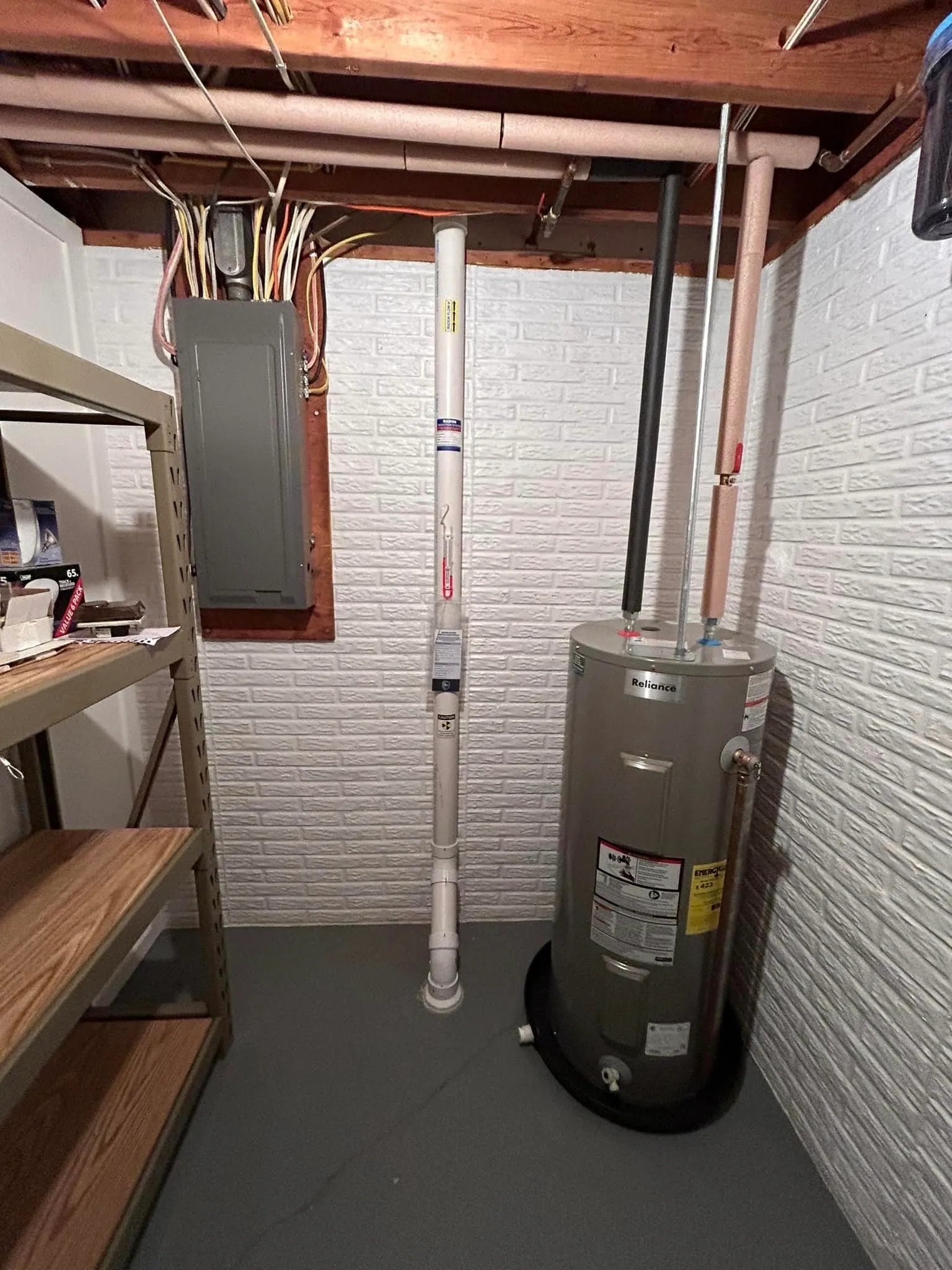 White radon pipe installed along a painted brick basement wall