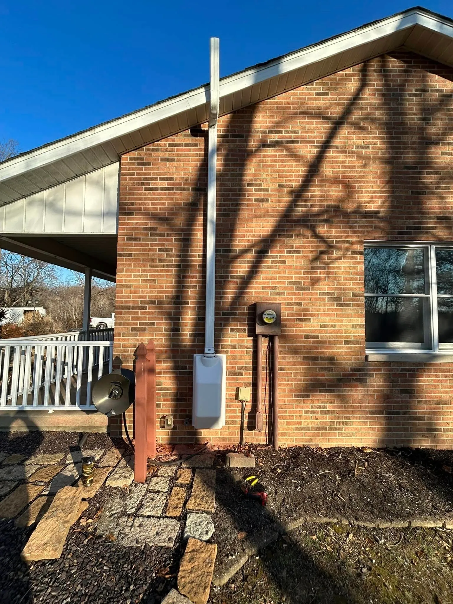 Exterior radon vent pipe beside a brick home